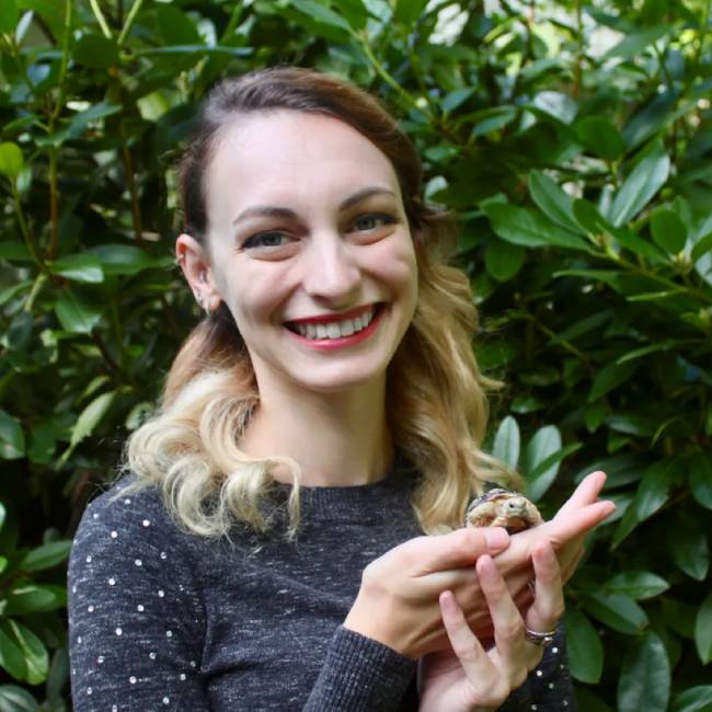 Associate veterinarian Dr. Lauren Spendley smiling and holding a small animal outdoors - pet urgent response and emergency